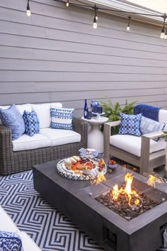 a fire pit sitting in the middle of a patio next to two couches and a table