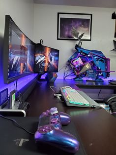 a gaming room with two monitors, a keyboard and a game controller on the desk