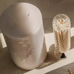 a white object sitting on top of a wooden table next to a glass vase and toothbrush holder