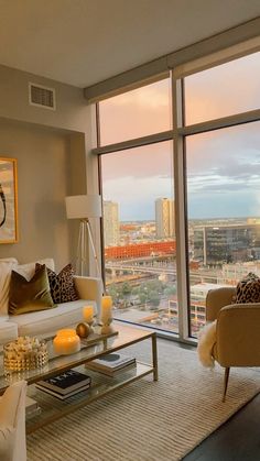 a living room filled with furniture and a large window overlooking the cityscape in the distance