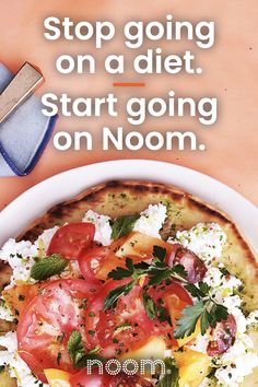 a pizza with tomatoes and feta cheese on it next to a knife, fork and napkin