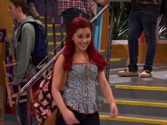 a girl with red hair is walking down the stairs in front of some other people