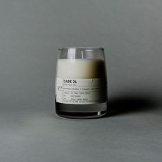 a candle sitting on top of a table next to a gray wall with the words candle 46 printed on it