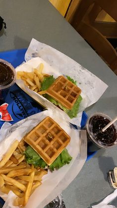 two waffle sandwiches and french fries on a blue plate with ketchup, mustard, and lettuce