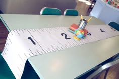 a table with a ruler on top of it and a small toy in the middle