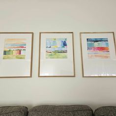 three paintings hang on the wall above a couch