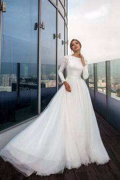 a woman standing on top of a building wearing a white dress