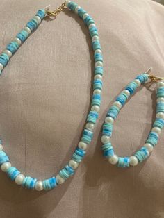 a pair of blue and white beaded necklaces on top of a beige pillow