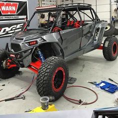 a gray and red vehicle in a garage with tools on the floor next to it