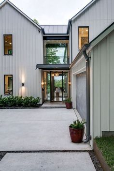 a large white house with lots of windows and plants in the front garden area on either side