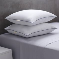 three pillows stacked on top of each other in front of a night stand and nightstand