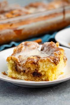 a piece of cinnamon roll sitting on top of a white plate next to a baking pan