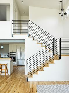 an open floor plan with stairs leading up to the kitchen and living room area in this modern home