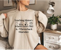 "Are you a proud history teacher or know someone who is? This \"Teaching History: Where Every Day is #Throwback Thursday\" sweatshirt is the perfect gift for history enthusiasts and educators alike! Featuring a witty and playful design, this sweatshirt combines the popular social media trend of #ThrowbackThursday with the timeless subject of history. With illustrations of historical icons that represent different eras, this sweatshirt is a unique and fun way to celebrate the love for history. The retro or vintage aesthetic of the sweatshirt adds a nostalgic touch, making it a perfect gift for history teachers who appreciate the significance of the past. Whether it's Mother's Day, Father's Day, Christmas, Teacher's Day, or Back-to-School Day, this sweatshirt is a thoughtful and humorous gif History Jokes, Social Studies Teacher, Social Media Trends, History Teachers, Teaching History, Throwback Thursday, Funny Sweatshirts, Teacher Humor, Back To School Gifts