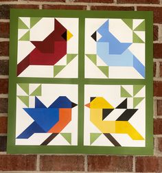 three colorful birds are on the wall next to a brick wall with green trimmings