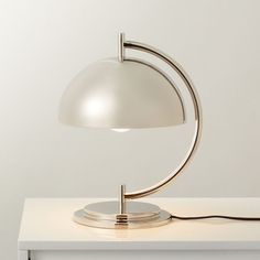 a white table lamp sitting on top of a white counter next to a light bulb