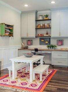 a kitchen with white cabinets and a table in front of the counter top, along with an area rug on the floor