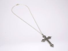 The cross pendant of this lovely piece is an elegantly crafted piece with many charming accents adorning it. It's forged from a strong 316L stainless steel material and finished in a polished silver coat. The exterior border and detailed outlines on this piece are smooth and clean-cut, while the interior India is covered in a rougher, granite-like surface. The contrasting textures are clear and highlight the details on the piece beautifully. The cross stands at 56 mm long. This Innovato Design piece comes with a 18" silver twisted Singapore chain.  Product Highlights:    Made from durable stainless steel silver  Elegant Cross Pendant Design  Twisted Singapore Chain Necklace (Length: 18") Spiritual Metal Cross Necklace, Spiritual Metal Cross Pendant Necklace, Spiritual Metal Pendant Cross Necklace, Elegant Metal Crucifix Cross Necklace, Metal Crucifix Cross Necklace As Gift, Metal Crucifix Cross Necklace Gift, Metal Crucifix Cross Necklace For Gift, Silver Stainless Steel Jewelry With Cross Pendant, Silver Stainless Steel Cross Pendant Jewelry