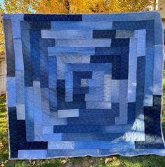 a blue and black quilt hanging from a tree