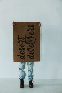 a person holding up a cardboard sign with writing on it