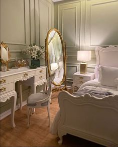 a bedroom with white furniture and gold accents on the walls, along with a large mirror