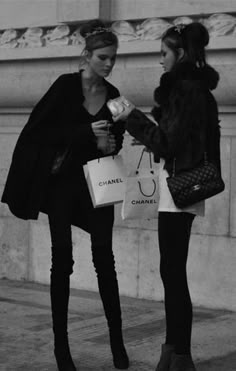 two women standing next to each other holding shopping bags