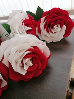 three red and white roses sitting on top of a table