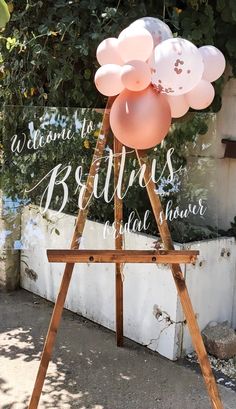 a wooden easel holding balloons in front of a sign