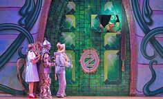 the wizard and his friends are standing on stage in front of a green door with an arch