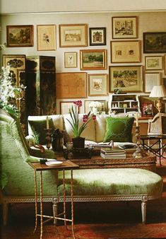 a living room filled with green furniture and pictures on the wall above it's coffee table