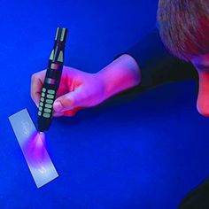 a young man holding a cell phone next to a piece of paper on a blue surface