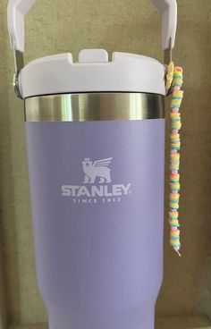 a purple tumbler with a straw in it sitting on a counter next to a wall