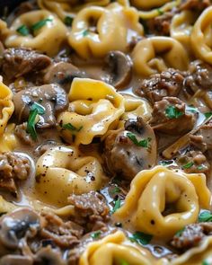 a skillet filled with pasta and meat covered in sauce, cheese and parsley