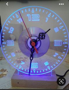 a clock that is sitting on top of a wooden block with blue light around it