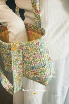 a woman is holding a purse made out of fabric and has flowers on the inside