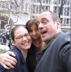 two women and a man taking a selfie in front of a building on a city street