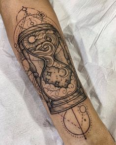 a black and white tattoo on the leg of a man with an hourglass in it