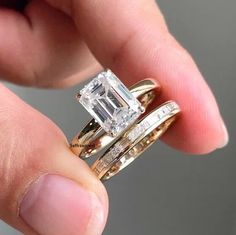 a person holding two wedding rings in their hand, one with a diamond on it