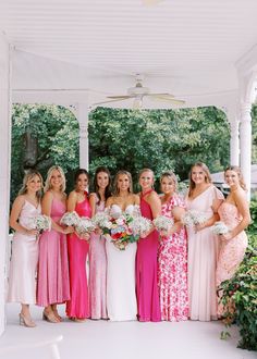 a group of women standing next to each other under a gazebo holding bouquets