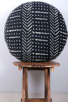 a black and white pillow sitting on top of a wooden stool