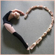 a woman in black shirt and leggings standing next to a heart shaped object