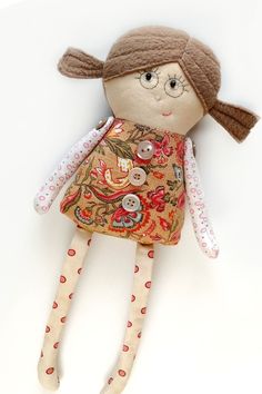 a doll with glasses and a dress on it's head is laying down against a white wall