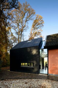 two black houses with red doors and windows on the outside, one has a person walking in