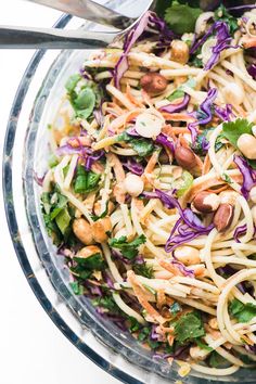 a glass bowl filled with noodles, beans and veggies next to a fork