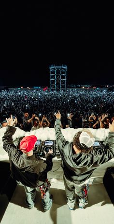 two people standing in front of a large crowd with their hands up to the sky