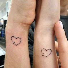 two people with matching tattoos on their arms, one is holding the other's hand