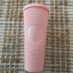 a pink starbucks cup sitting on top of a white table next to a brown rug