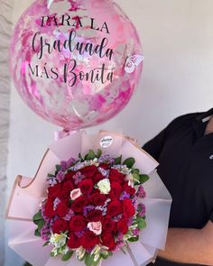 a woman holding a bouquet of red roses and a pink balloon with congratulations written on it