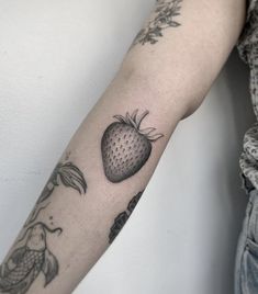 a woman's arm with a strawberry tattoo on it