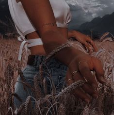 a woman standing in the middle of a wheat field with her hands wrapped around her waist